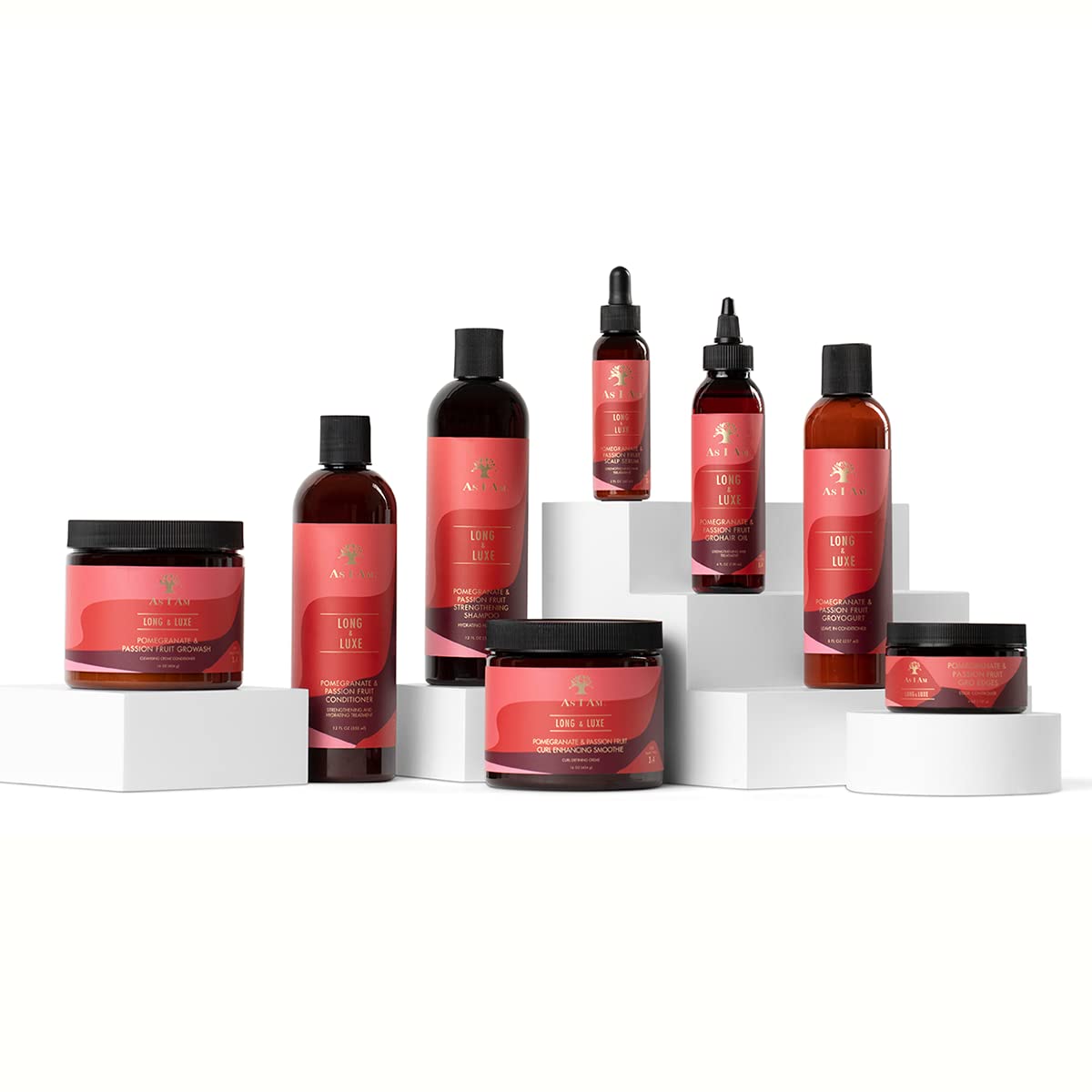 Billedet viser As I Am Long and Luxe Strengthening Shampoo, Conditioner, GroHair Oil og andre produkter fra serien, arrangeret på hvide podier mod en hvid baggrund.