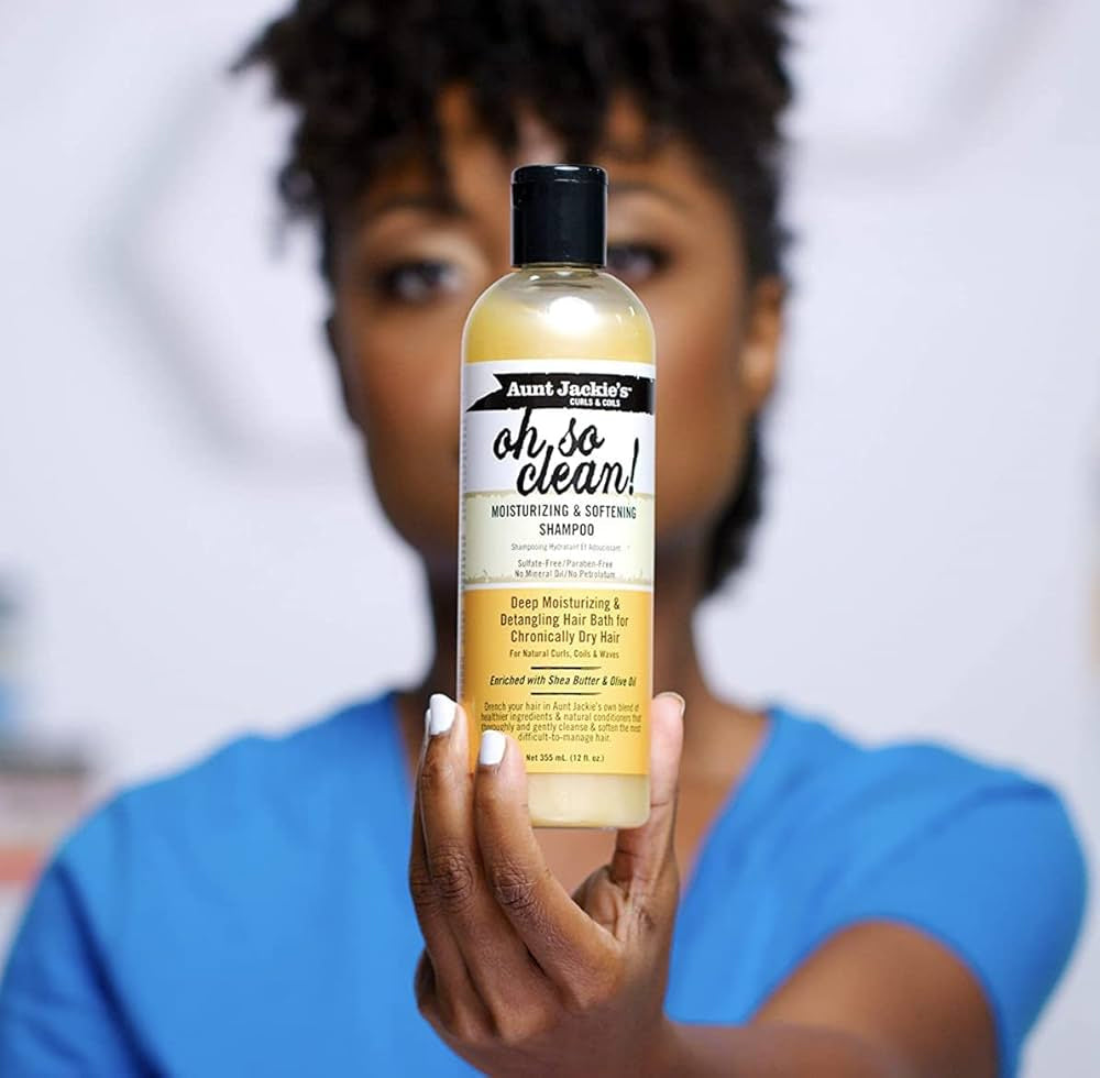 Nærbillede af en kvinde der holder Aunt Jackie's Curls & Coils Oh So Clean Moisturizing & Softening Shampoo.