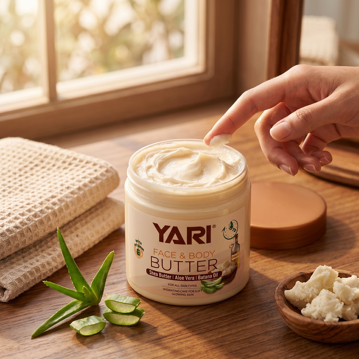 Yari Face & Body Butter med shea, aloe vera og batana olie på træbord med finger der tager creme.